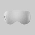 A light grey fabric far-infrared hot and cold eye massager with a textured mesh pattern and a small circular control on the left side.